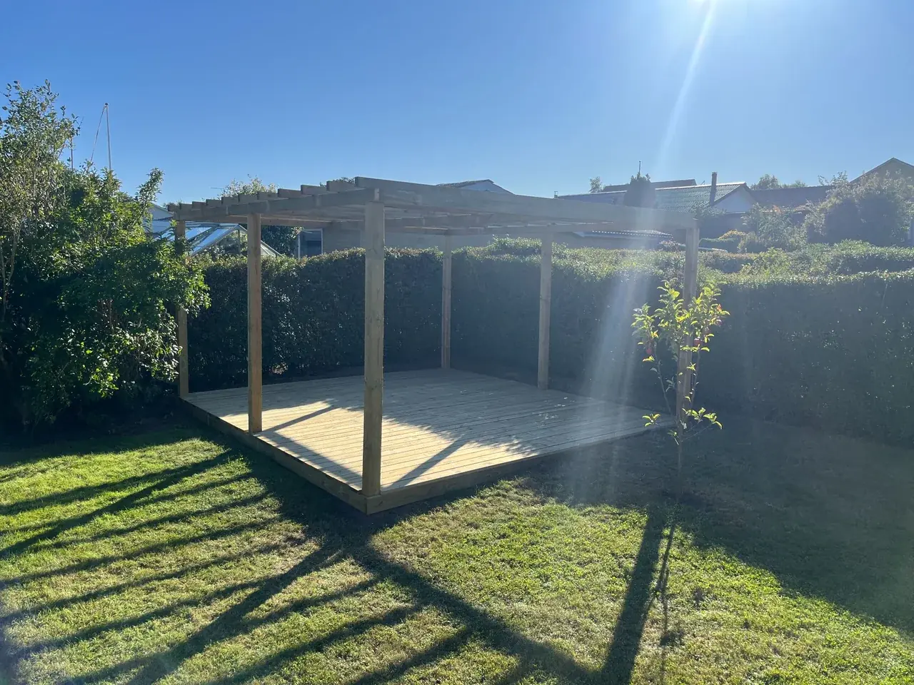 En færdig træterrasse med pergola.
